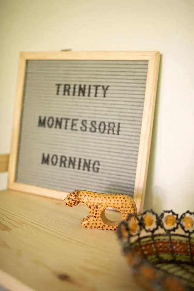 Letterboard reading 'Trinity Montessori Morning' next to a hand-carved leopard figurine and decorative basket