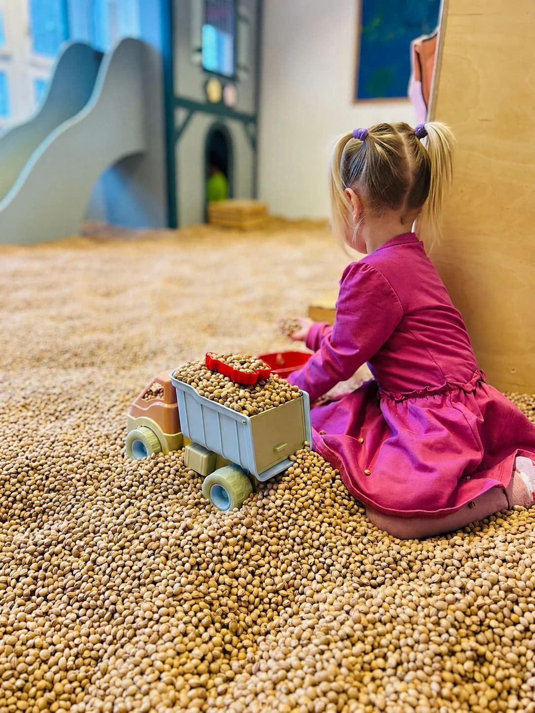 Child playing with a toy truck on cherry stones in the Cherry Stone Room