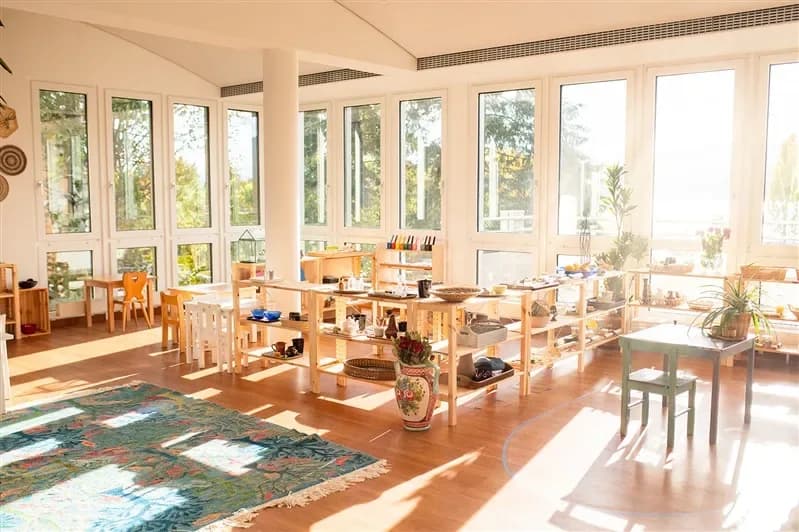 Ein lichtdurchfluteter, von Fenstern umgebener Montessori-Raum mit Seeblick am Serendipity Campus